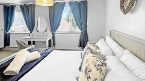 Hotellihuone, jossa on sänky, työpöytä, tuoli, peili ja seinälle kiinnitetty sydämenmuotoinen koriste.