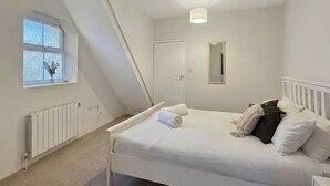 Ein Schlafzimmer mit Bett, Fenster, Heizkörper und Tür.