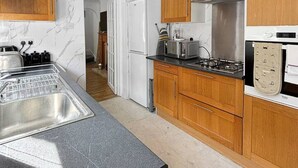 A modern kitchen with wooden cabinets, a black countertop, and a stainless steel sink. - 3bed house Sleeps8 garden driveway Free Gym Access (Lincolnshire)