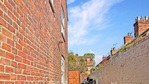A narrow brick alleyway with a paved path, flanked by red brick buildings and a stone wall. - 3bed house Sleeps8 garden driveway Free Gym Access (Lincolnshire)