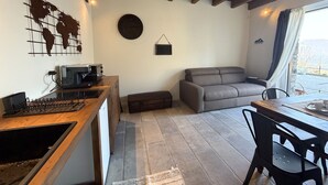 A cozy living space with a wooden table, a gray sofa, a coffee machine, and a world map on the wall. - Enchantment of the Lake app Riva Two-room apartment with Terrace and A/C (Molina)