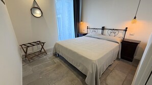 A bedroom with a bed, a nightstand, a lamp, a mirror, and a window with curtains. - Enchantment of the Lake app Riva Two-room apartment with Terrace and A/C (Molina)