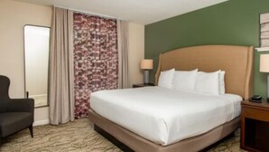 A hotel room with a bed, a chair, a nightstand, and a mirror. - CW BLOCK Angels Camp 2br (Angels Camp)