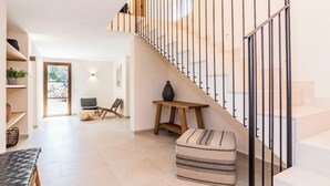 Um interior moderno com escada, um banco, uma pequena mesa e um sofá.