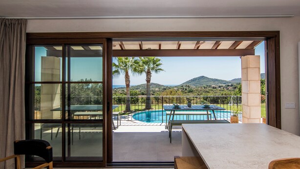 Quarto moderno com uma grande porta de vidro deslizante que dá para uma área de piscina ao ar livre e vista para colinas.