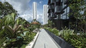 A pathway lined with greenery, a small pavilion, and tall buildings in the background. - Smart Loft-style 1br Apt Near to Shops (Panama City)