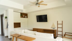 A modern living room with a white sofa, wooden coffee table, and a TV mounted on the wall. - Exclusive Villa With 2 Bedrooms and Shared Pool (Taxisco)