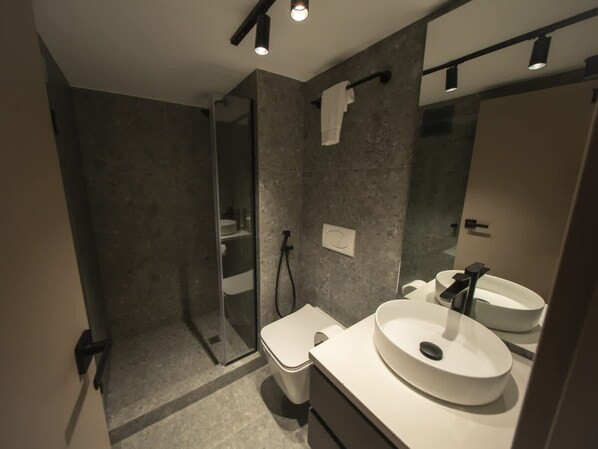 A modern bathroom with a walk-in shower, a toilet, a sink with a mirror, and a towel rack. - Brand new Loft for 3 Guests in Unique Tower (Panama City)