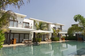 A modern hotel with a pool, outdoor seating, and palm trees. - Villa With Direct Pool Access in Gathered Complex (Taxisco)
