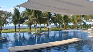 Ein Swimmingpool mit Palmen und Blick auf den Ozean.