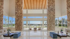 A spacious lobby with a high ceiling, large windows, and a view of a golf course. - Stunning 6br Villa With Ocean View in Cap Cana (Punta Cana)
