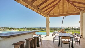 An outdoor patio with a pool, wooden furniture, and a view of the ocean. - Stunning 6br Villa With Ocean View in Cap Cana (Punta Cana)