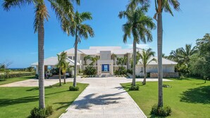 A hotel with a central entrance, palm trees, and a clear sky. - Stunning 6br Villa With Ocean View in Cap Cana (Punta Cana)