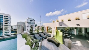 A rooftop pool area with lounge chairs, a bar, and a view of the cityscape. - Flat in Regatta Ii 306 (Santo Domingo)