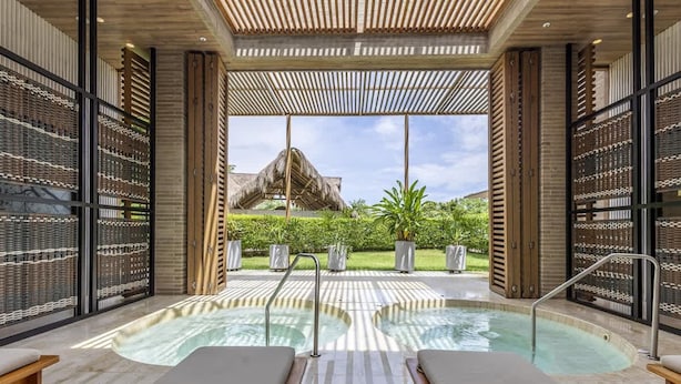 A spa area with a hot tub, lounge chairs, and a view of a thatched-roof structure. - Oceanview Penthouse w Terrace gym (Cartagena)