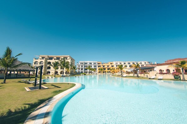 A resort with a large swimming pool, palm trees, and multi-story buildings. - Studio 3 Guests Balcony With Views Fishing Lodge (Punta Cana)
