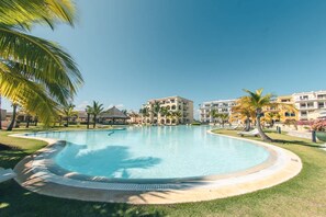 A swimming pool surrounded by palm trees and a resort building. - Studio 3 Guests Balcony With Views Fishing Lodge (Punta Cana)