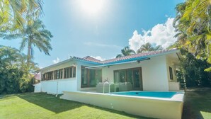 A modern house with a swimming pool, large windows, and a well-maintained lawn. - 3br Villa Private Pool 6 Guests in Casa de cam (La Romana)