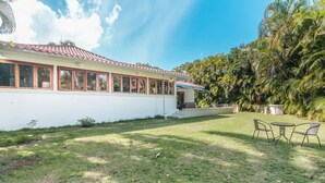 A house with a white exterior, a tiled roof, and a small front porch with two chairs. - 3br Villa Private Pool 6 Guests in Casa de cam (La Romana)