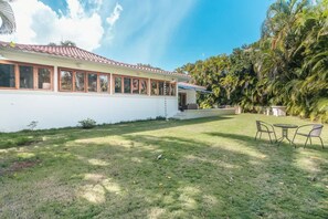 Ein Haus mit weißer Fassade, einem Ziegeldach und einer kleinen Veranda mit zwei Stühlen.
