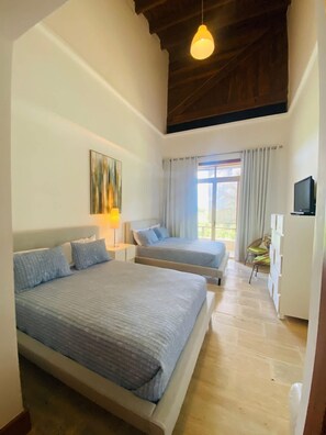 Quarto com duas camas, uma televisão e uma janela com cortinas.