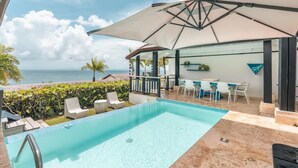 Ein Pool mit Meerblick, Sitzgelegenheiten im Freien und einem überdachten Bereich.