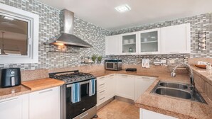 Eine moderne Küche mit Gasherd, Mikrowelle, Spüle aus Edelstahl und weißen Schränken.