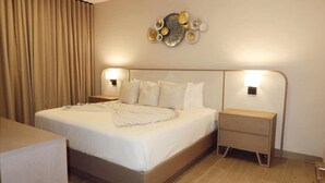 A hotel room with a large bed, bedside tables, a wall-mounted light fixture, and a curtain. - 2br 4 Guests Balcony and Pool View Cap Cana (Punta Cana)