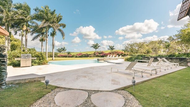 A swimming pool with lounge chairs and palm trees. - Modern 2br-apartment w Golf View at Casa de Campo (La Romana)