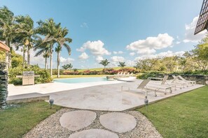 A swimming pool with lounge chairs and palm trees. - Modern 2br-apartment w Golf View at Casa de Campo (La Romana)