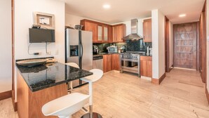 A modern kitchen with wooden cabinets, a black countertop, and a built-in oven. - Modern 2br-apartment w Golf View at Casa de Campo (La Romana)