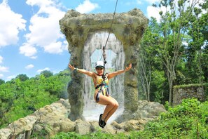 A person bungee jumping from a natural rock formation with a waterfall in the background. - Cozy 1br w Balcony Pool Beach Access Cap Cana (Punta Cana)