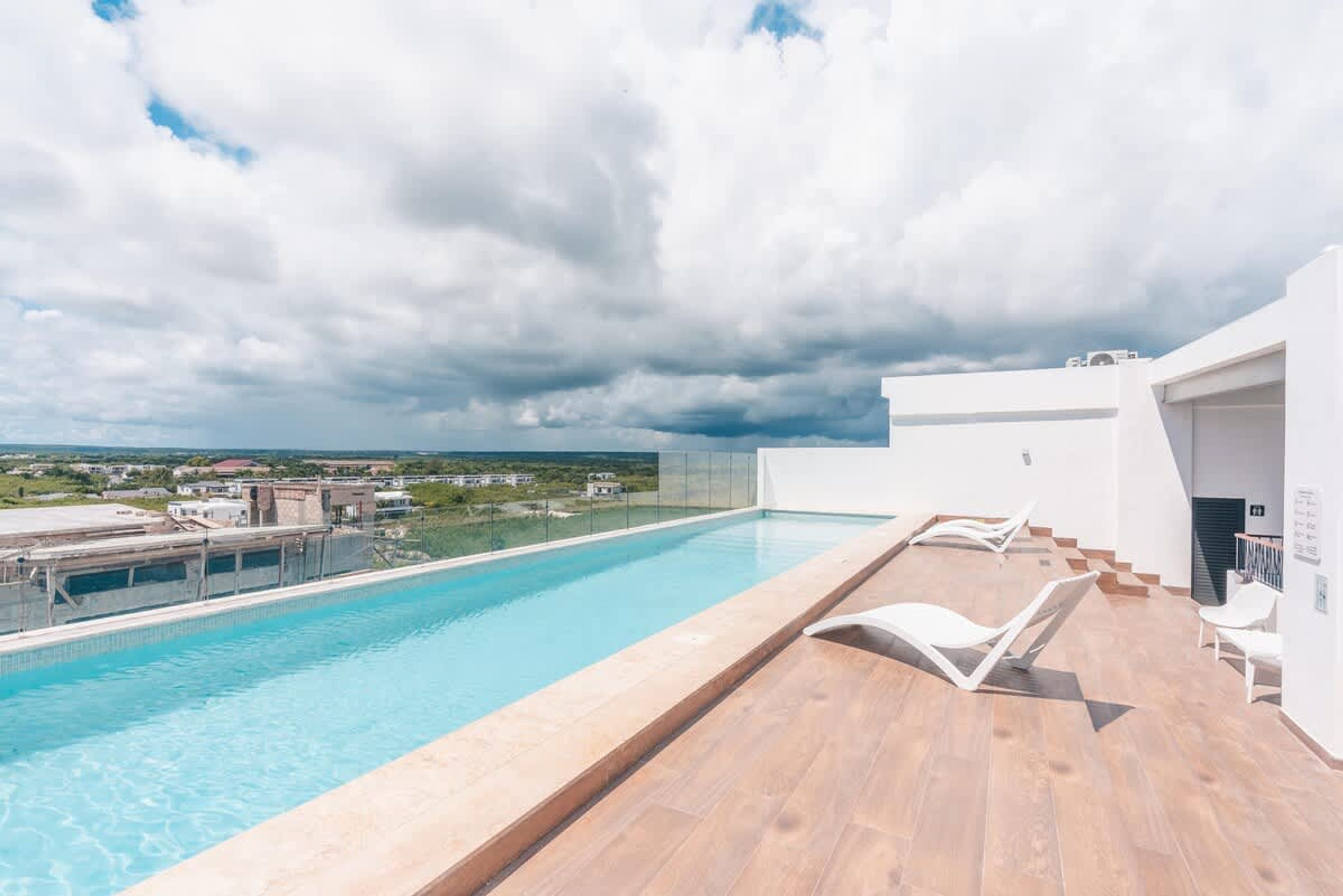 En pool på taket med utsikt över landskapet, ett trädäck och en modern arkitektonisk design.