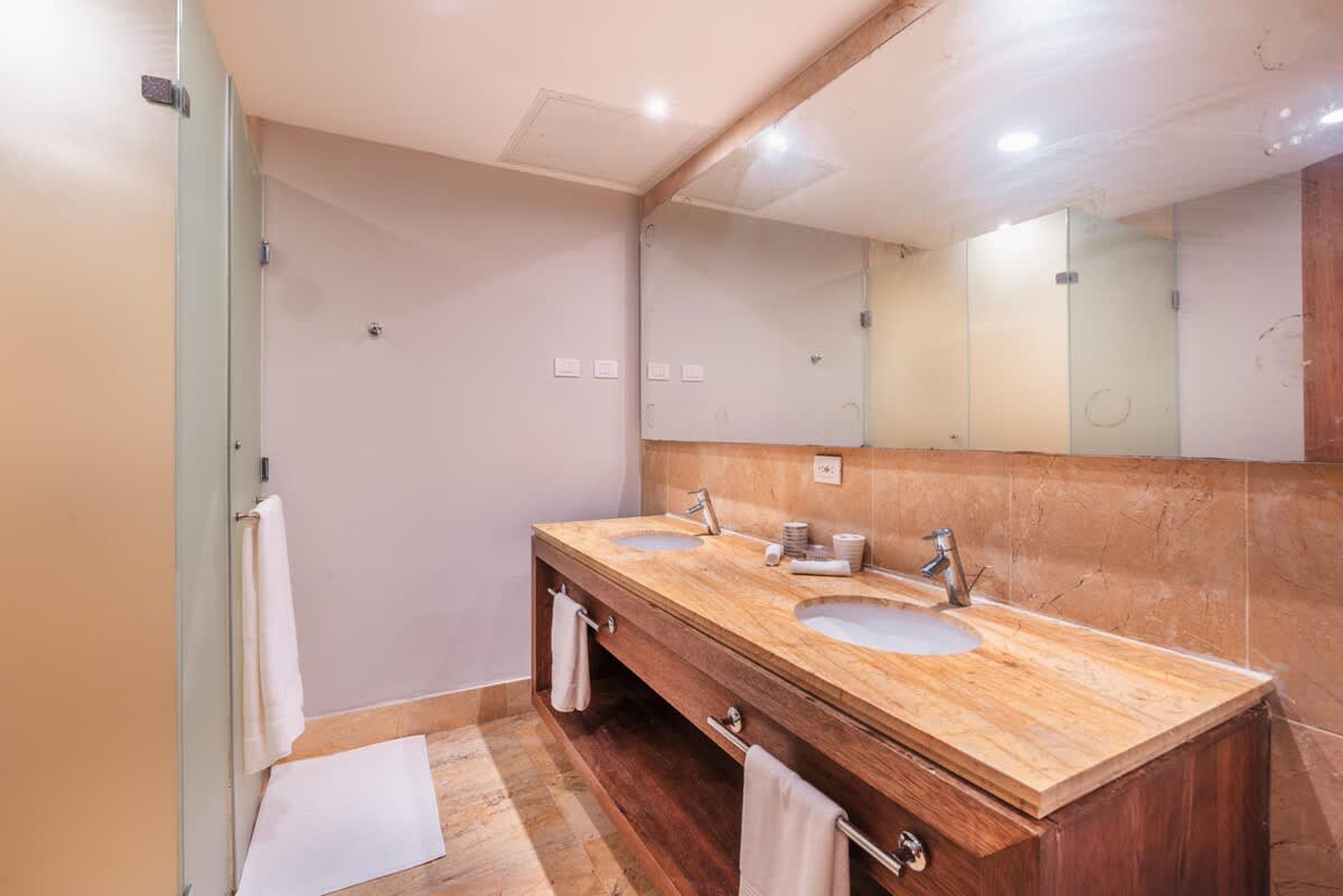 A bathroom with two sinks, a large mirror, and wooden cabinetry.