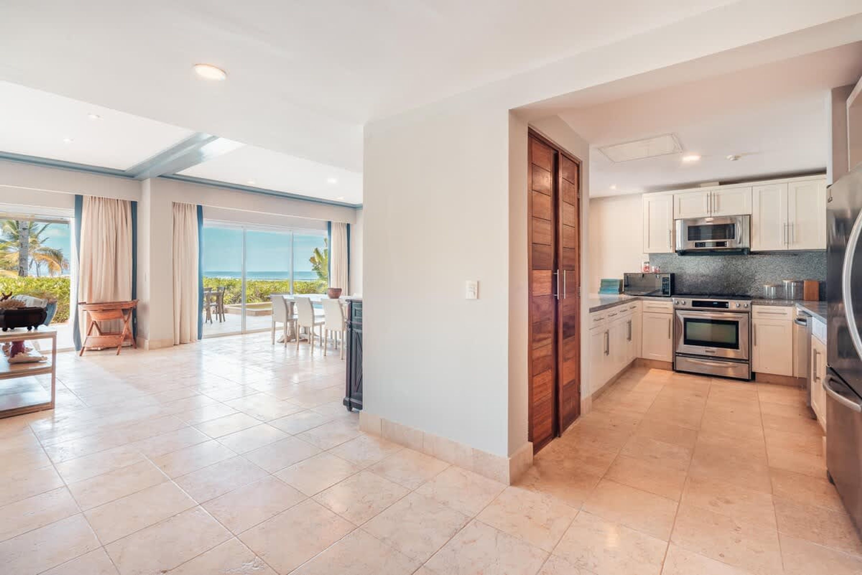 A modern kitchen with stainless steel appliances, a dining area with a view, and a spacious living area with a large window.