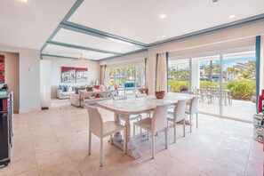 Un vaste espace de vie comprenant une table à manger, des canapés et une grande porte-fenêtre coulissante donnant sur un balcon.