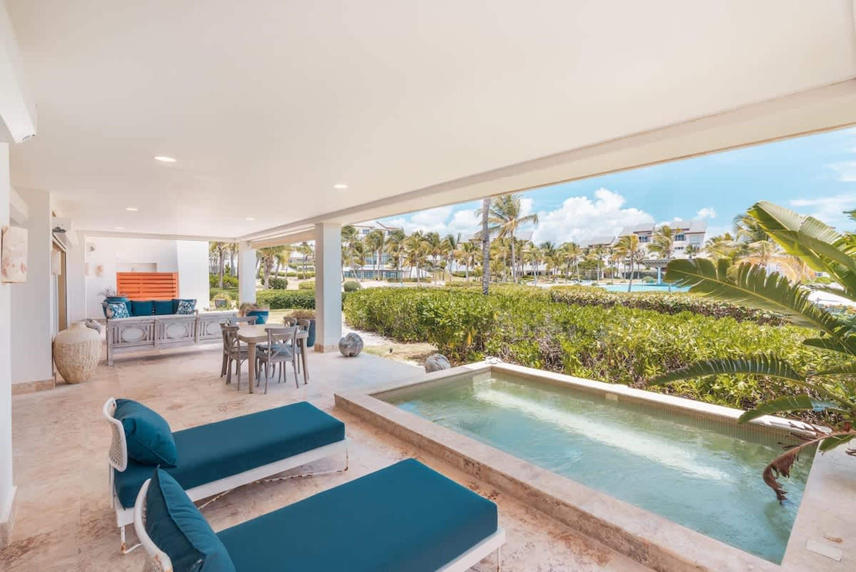 A pool area with lounge chairs, a table, and a view of a resort.