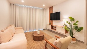 Un salon moderne avec un canapé, une table basse, un téléviseur et des plantes.