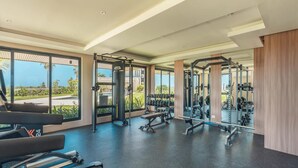 Une salle de sport équipée de matériel d’exercice, dotée de grandes fenêtres et offrant une vue sur l’extérieur.