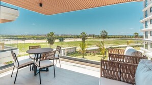 Un balcon doté d’un plafond en bois, une table ronde avec des chaises et une vue sur un paysage verdoyant.