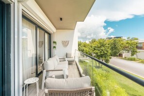 A balcony with a sofa, chairs, and a small table. - Two Bedroom Apartment With Balcony in cap Cana (Punta Cana)