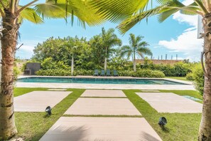 A swimming pool with a clear view of the surrounding greenery and a paved walkway. - Two Bedroom Apartment With Balcony in cap Cana (Punta Cana)