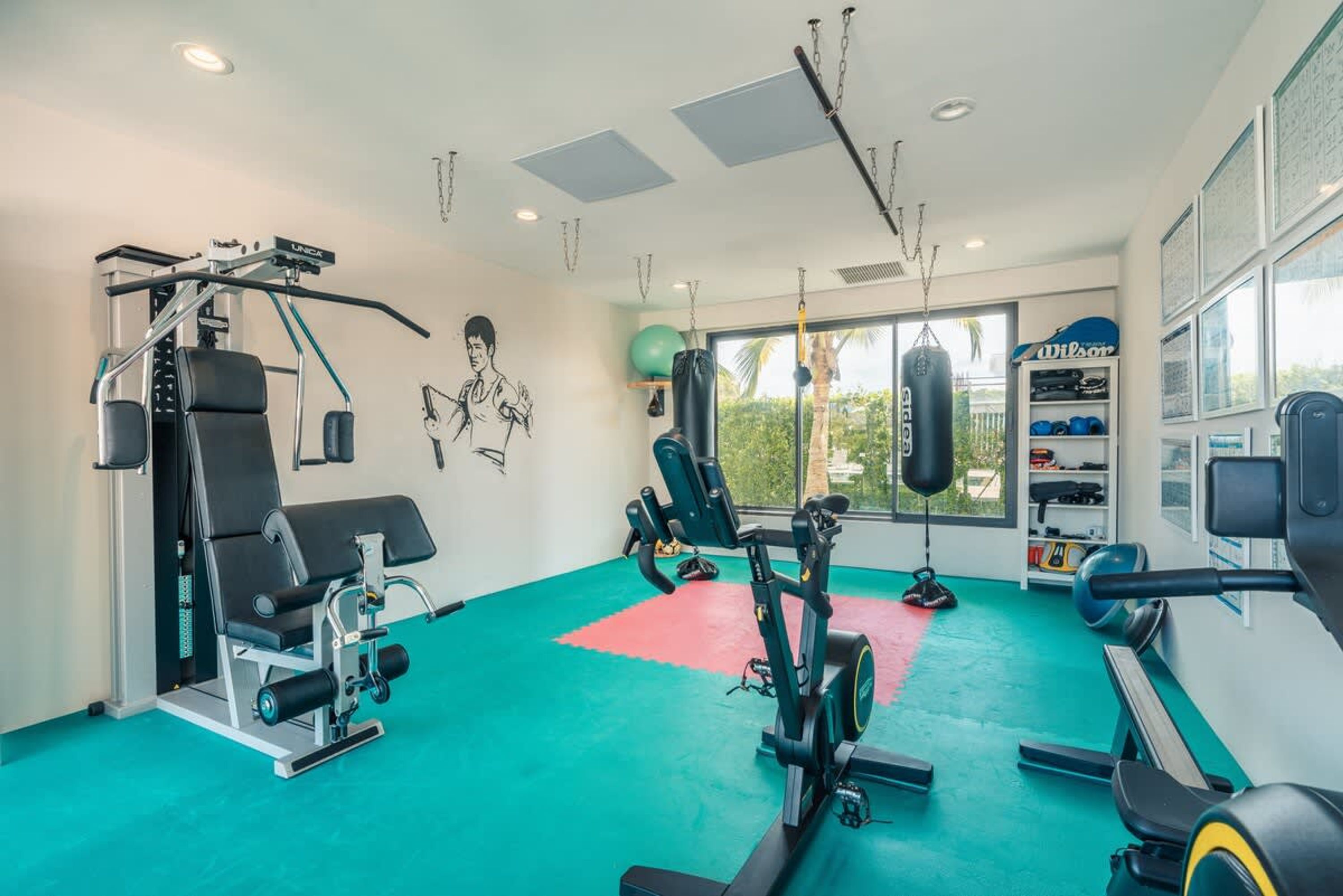 A gym with exercise equipment, a punching bag, and a view of the outdoors.