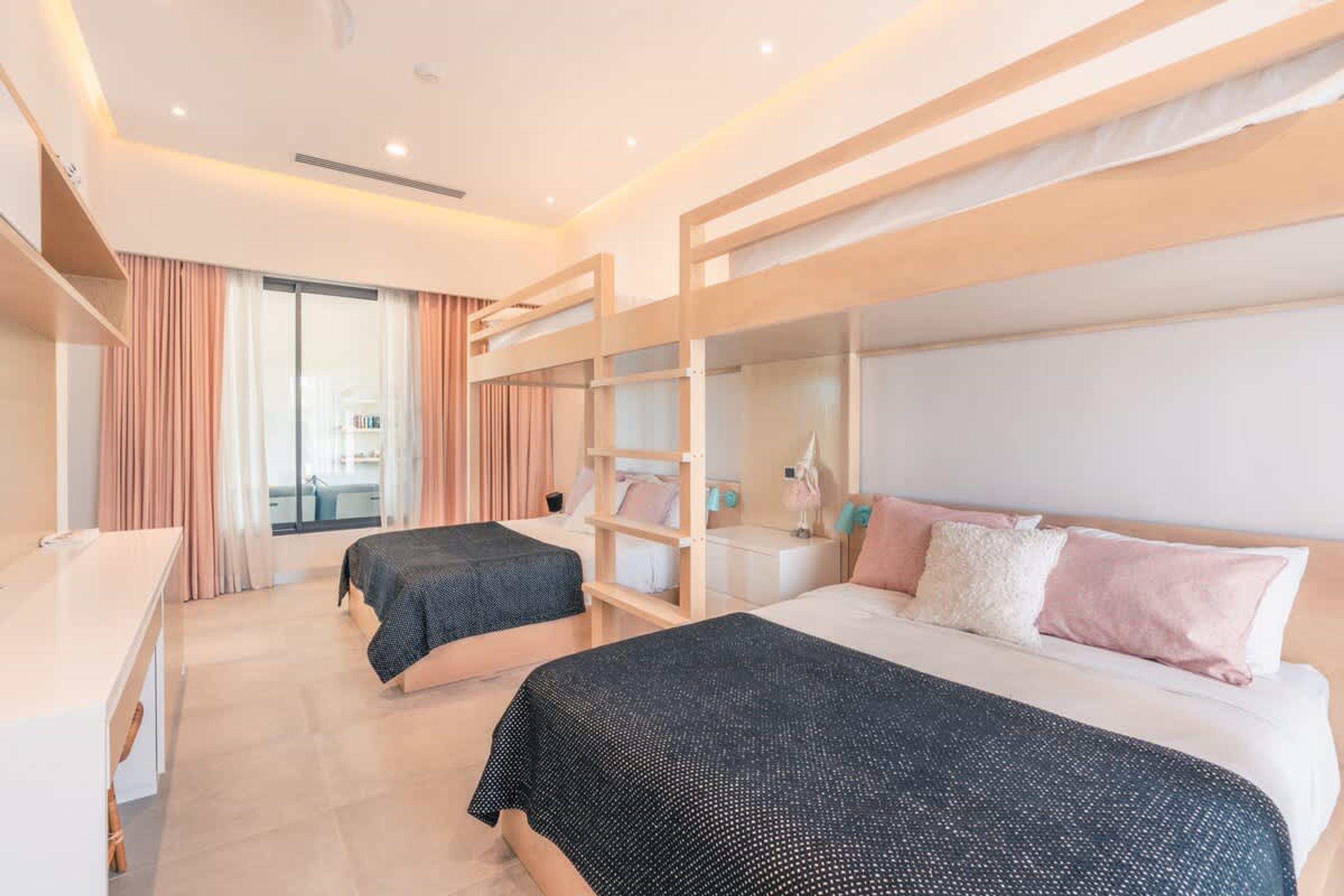 Een moderne hotelkamer met stapelbedden, een bureau en een groot raam.