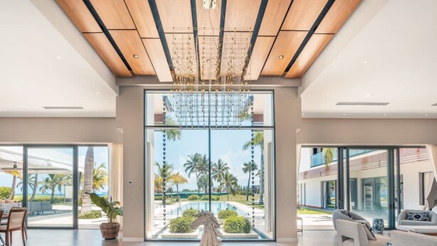 A spacious interior with a large glass door leading to a pool area, a chandelier, and modern furniture.