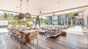 A spacious outdoor dining area with a long wooden table and chairs, a sofa, and a ceiling fan.