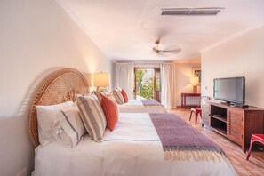 A hotel room with two beds, a TV, a wooden cabinet, and a ceiling fan. - Prime Location 5 Bedrooms 16 Guests Casa de Campo (La Romana)
