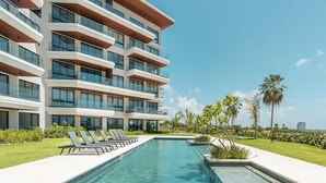 Un hotel moderno con piscina, tumbonas y palmeras.