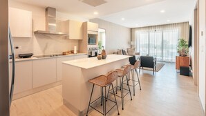 Una cocina moderna con una isla central, taburetes de bar y un comedor con sofá y mesa.