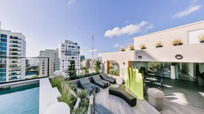 A rooftop pool area with a seating area, a bar, and a view of the cityscape. - Regatta Living Ii - 502 (Santo Domingo)